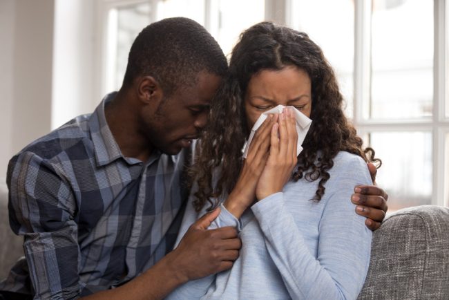 SupportiveAfricanHusbandEmbracingCryingWifeAskingForForgivenessOr man-hugging-chronically-ill-spouse-crying-on-couch-sad