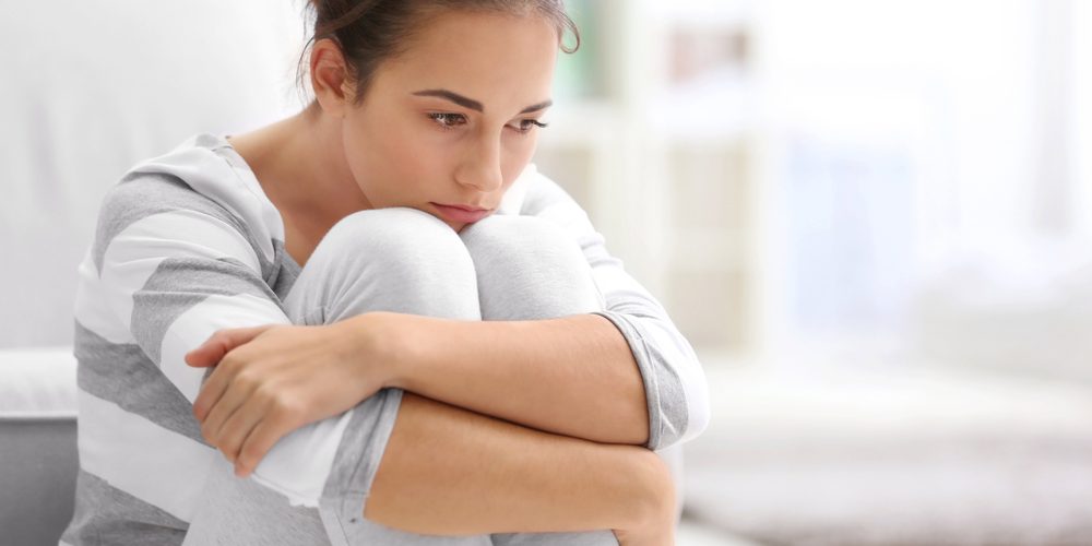 Depressed,Young,Woman,Sitting,On,Floor,At,Home Woman grieving in her home after diagnosed with a chronic illness.